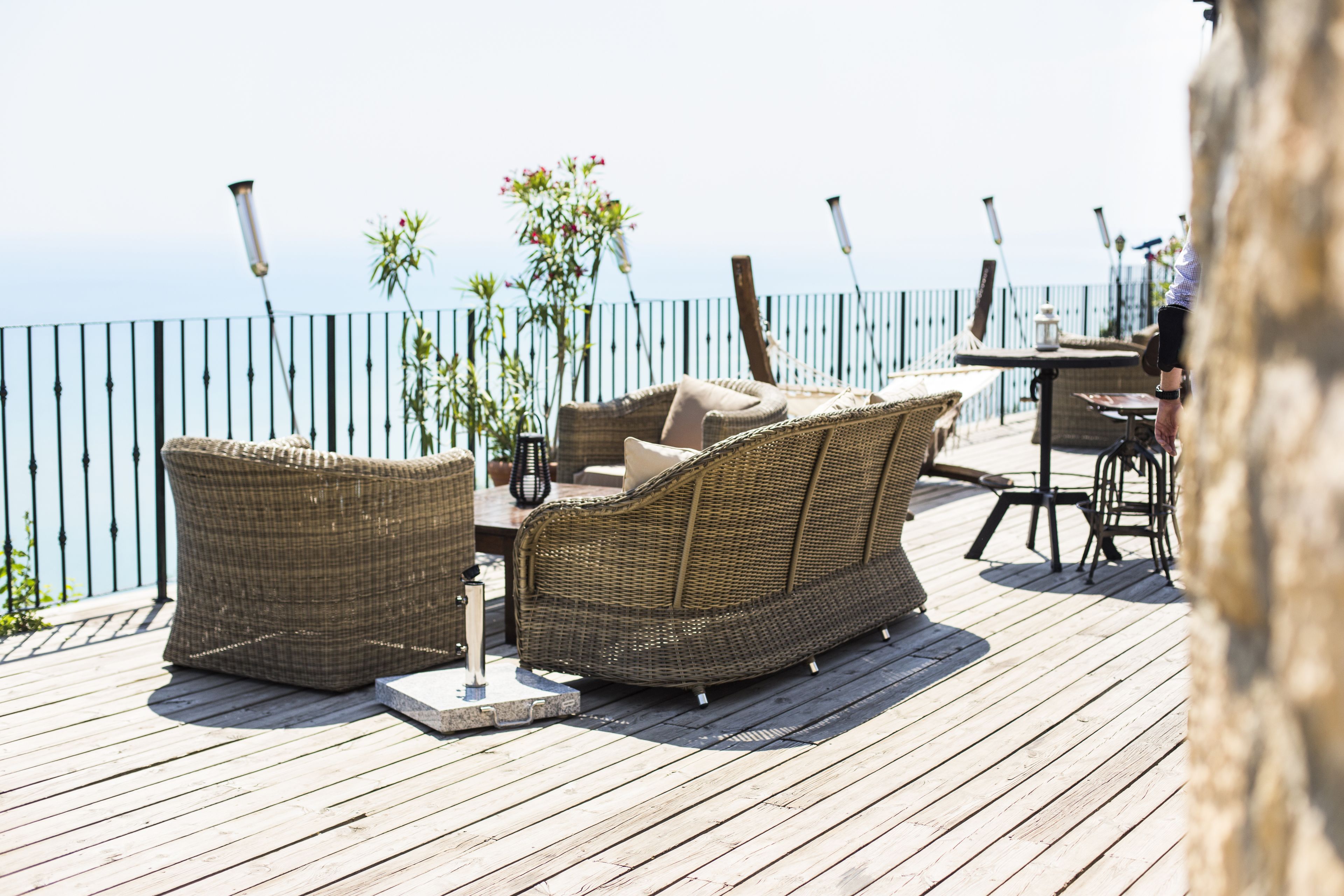 Una terraza de madera con muebles de mimbre, una mesa y sillas.