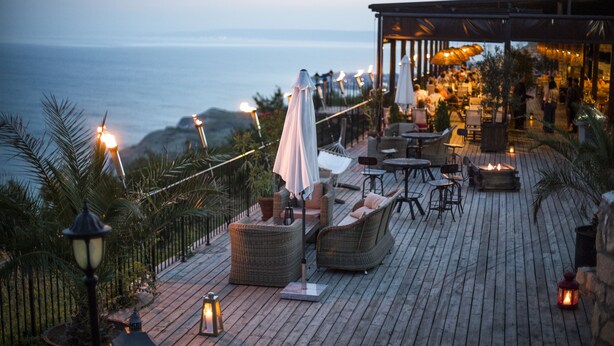 A wooden deck with outdoor seating, a fire pit, and a view of the ocean. - Kaliakria Resort (Kavarna)