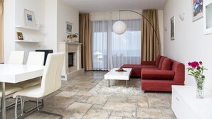 A modern living room with a white dining table, red sofa, and a fireplace. - Kaliakria Resort (Kavarna)