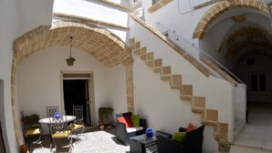 Un patio con zona de comedor, mobiliario exterior y una escalera que lleva a un nivel superior.