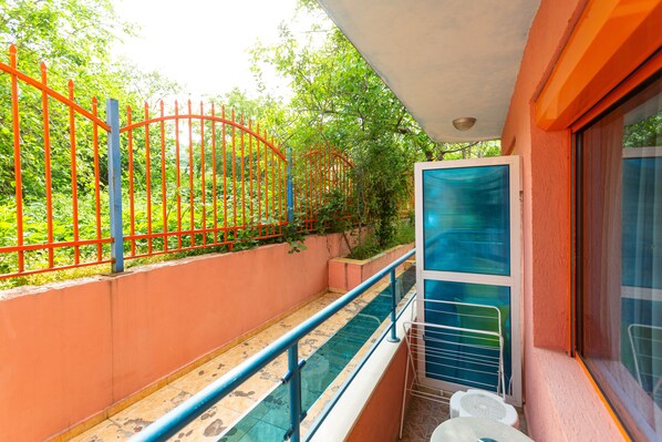 Un balcon doté d’une balustrade en verre, donnant sur une piscine et bordé d’une clôture rouge.