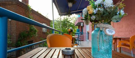 A wooden table with a blue vase of flowers and a tag.
