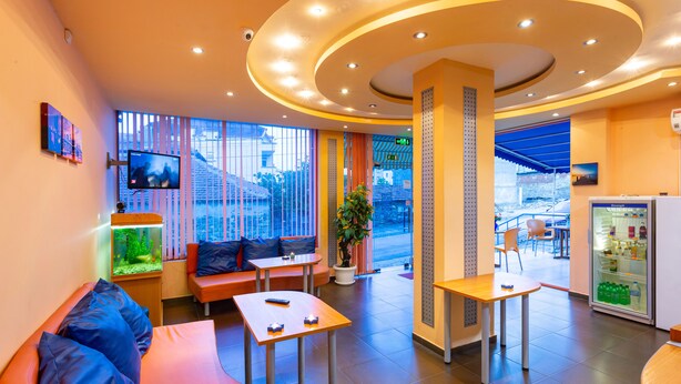 A modern hotel lobby with seating areas, a television, a plant, and a refrigerator. - Family Hotel Jemelly (Obzor)