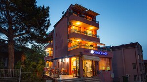 A multi-story hotel with a balcony on the second floor, a sign reading "Hotel Gemelli," and outdoor seating. - Family Hotel Jemelly (Obzor)