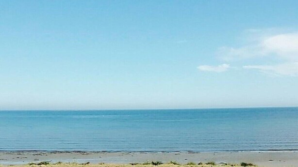 Una playa con cielos despejados y aguas tranquilas.