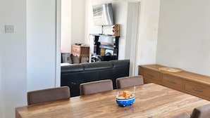 Un comedor con una mesa y sillas de madera, un pequeño barco decorativo en la mesa, y un espejo que refleja la habitación.