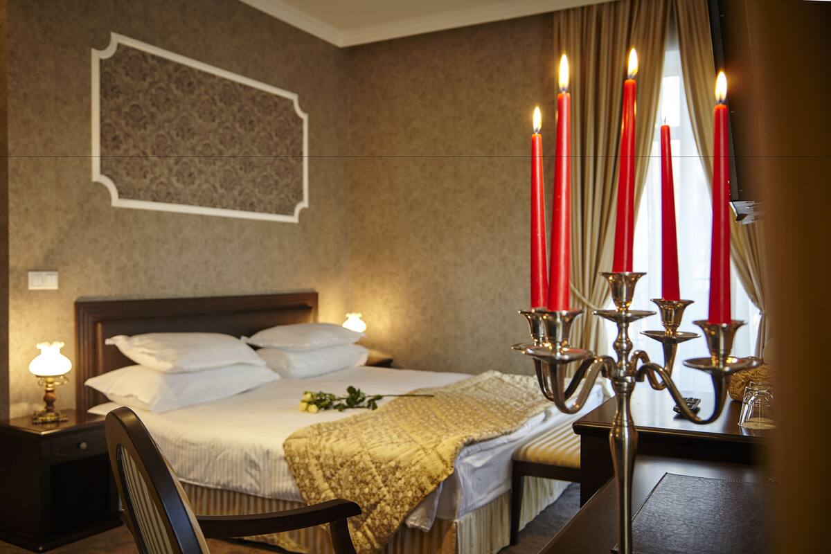 Une chambre d’hôtel avec un lit, une table de chevet, une lampe et un chandelier avec des bougies.