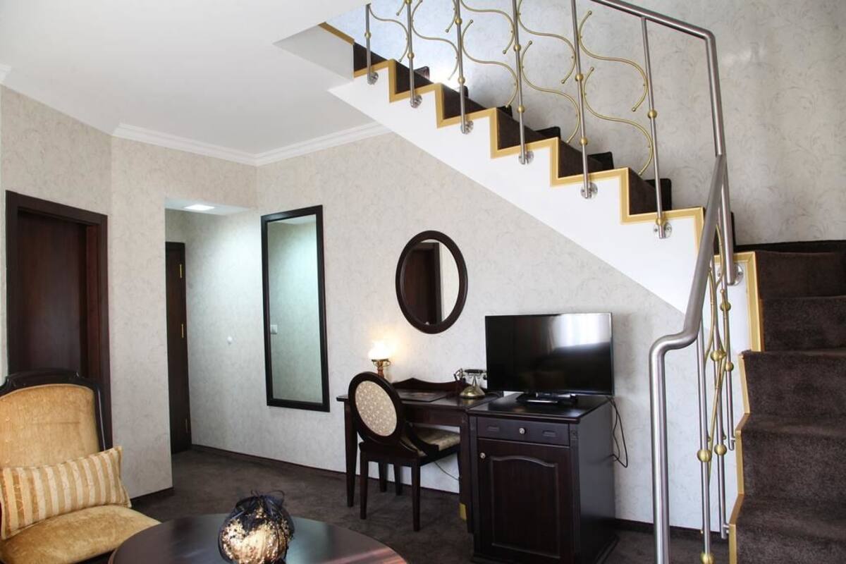 Une chambre d’hôtel avec un escalier, un bureau avec une télévision, une chaise et un canapé.