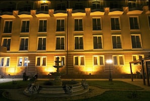 Un edificio de varios pisos con un patio central que cuenta con una fuente y una pérgola.