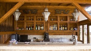 Uma área de bar com prateleiras de madeira repletas de garrafas, uma máquina de café e uma estátua de Buda.