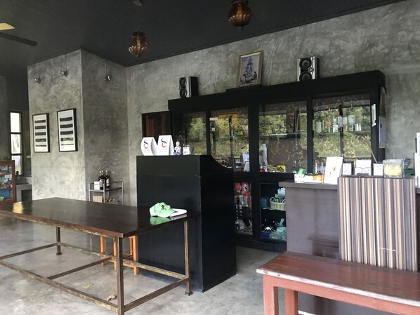 A reception area with a counter, framed pictures, and a large window. - Doembangvilla (Doem Bang Nang Buat)