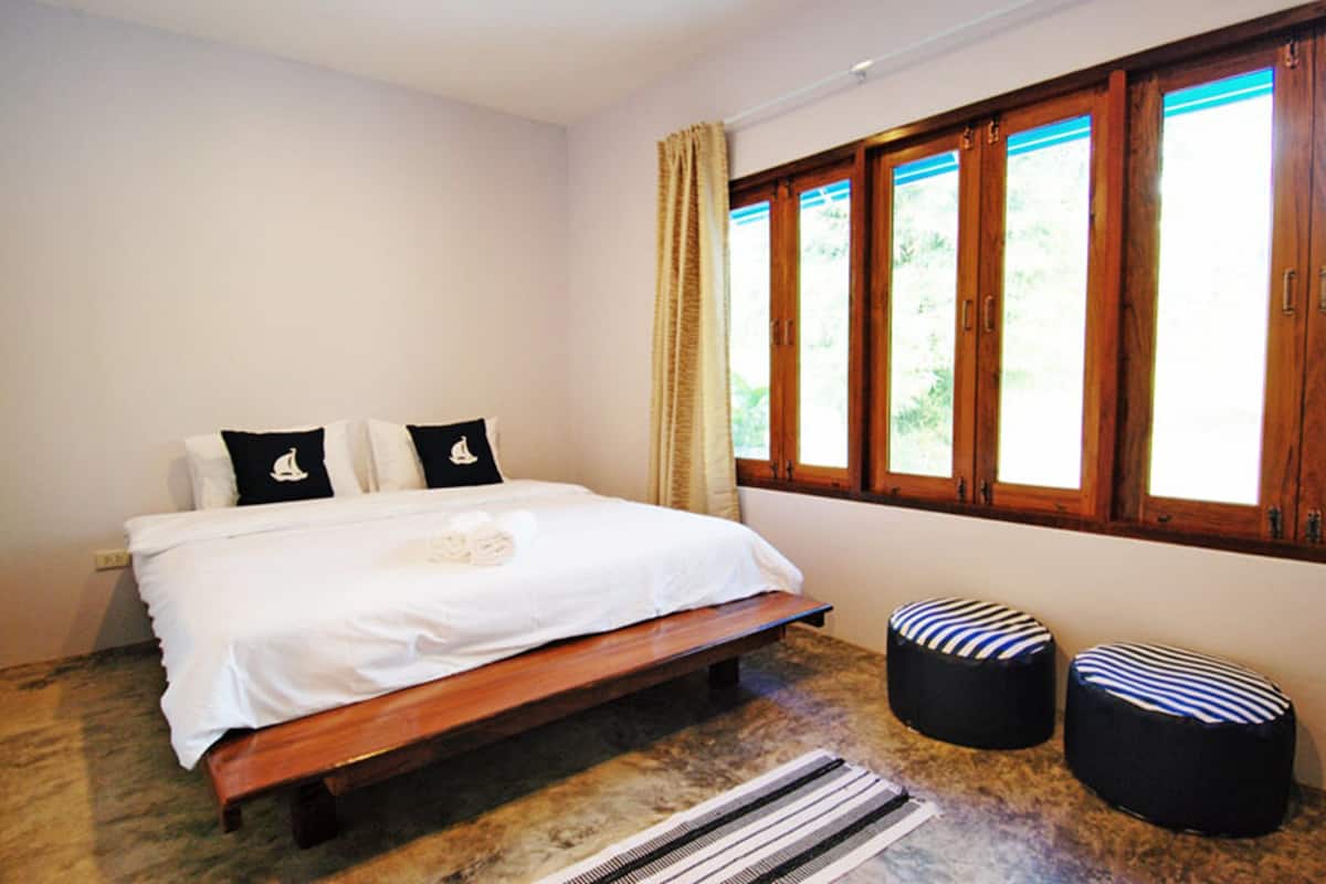 A bedroom with a bed, two pillows, a bench, and two ottomans.
