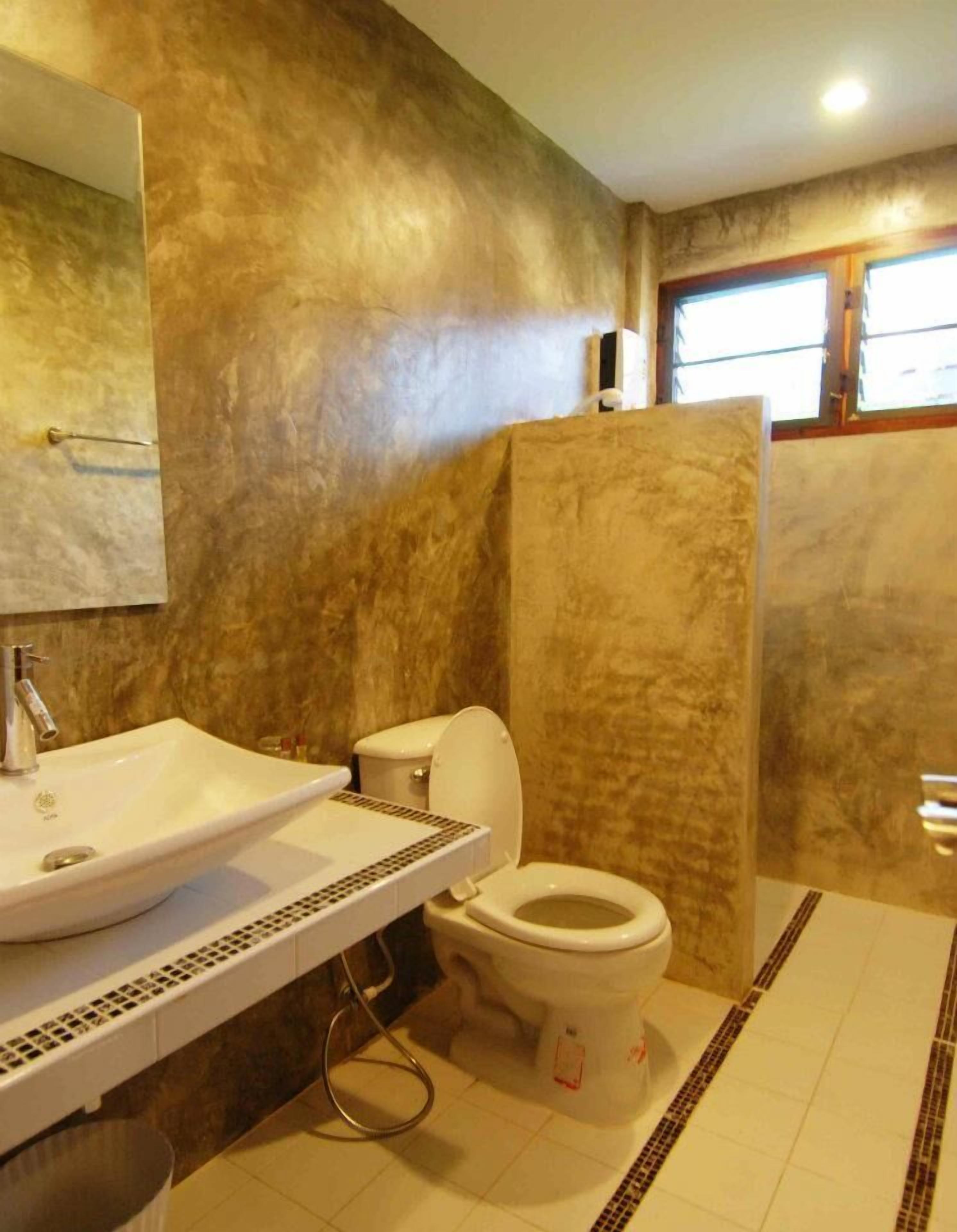 A bathroom with a large sink, toilet, and a shower enclosure.