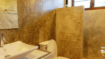 A bathroom with a large sink, toilet, and a shower enclosure.