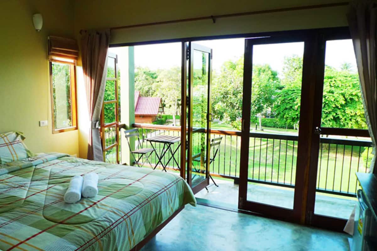 A bedroom with a bed, a window, and a balcony with a table and chairs.