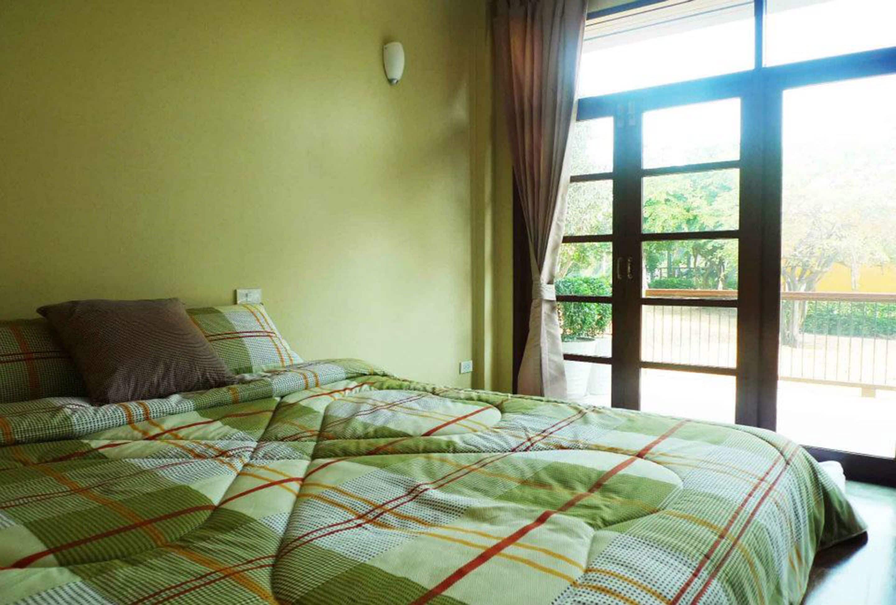 A room with a bed, a window, and a wall-mounted light fixture.