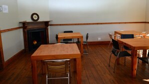 Une pièce dotée d’un plancher en bois, d’une cheminée, ainsi que de plusieurs tables et chaises en bois.
