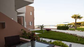 A balcony with wicker furniture, a glass table, and a potted plant.
