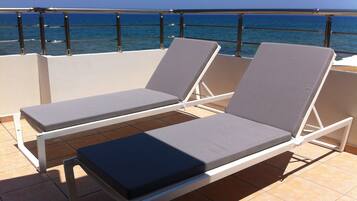 Dos sillones con cojines en un balcón con vista al mar.