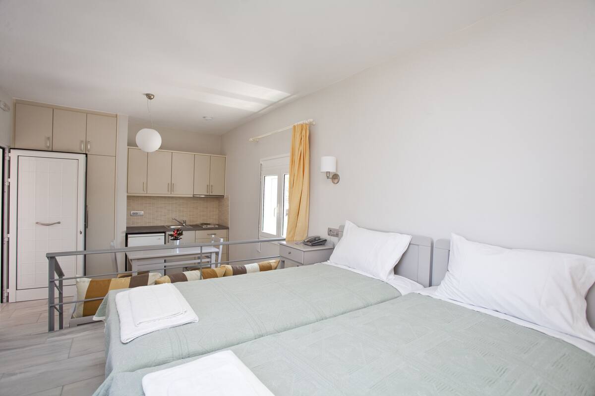 Habitación de hotel con cama, escritorio, silla, kitchenette y baño.
