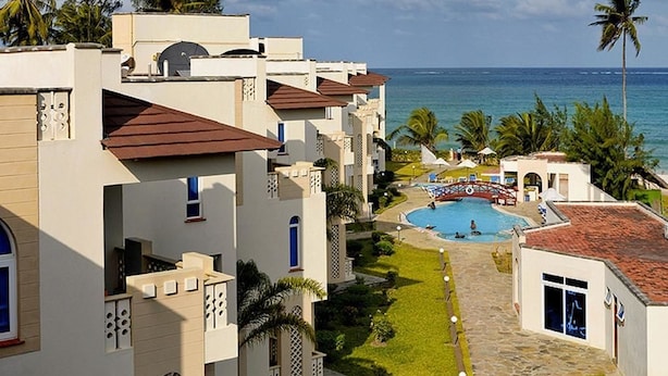 Ein Resort mit Schwimmbad, Palmen und Blick auf den Ozean.