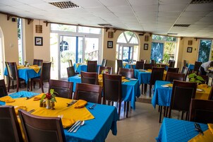 Un comedor con mesas dispuestas para varias personas, con manteles azules y sillas de madera.