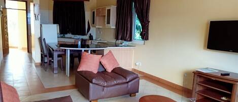 A living room with a brown leather sofa, a wooden coffee table, and a TV stand.