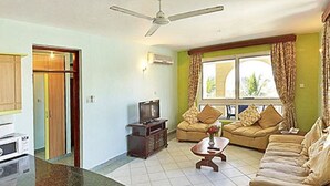 Ein Wohnzimmer mit einer Couch, einem Couchtisch, einem Fernseher und einem Deckenventilator.