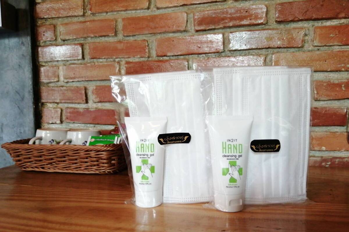 A set of hand cleansing gel tubes and a tissue box on a wooden surface against a brick wall.