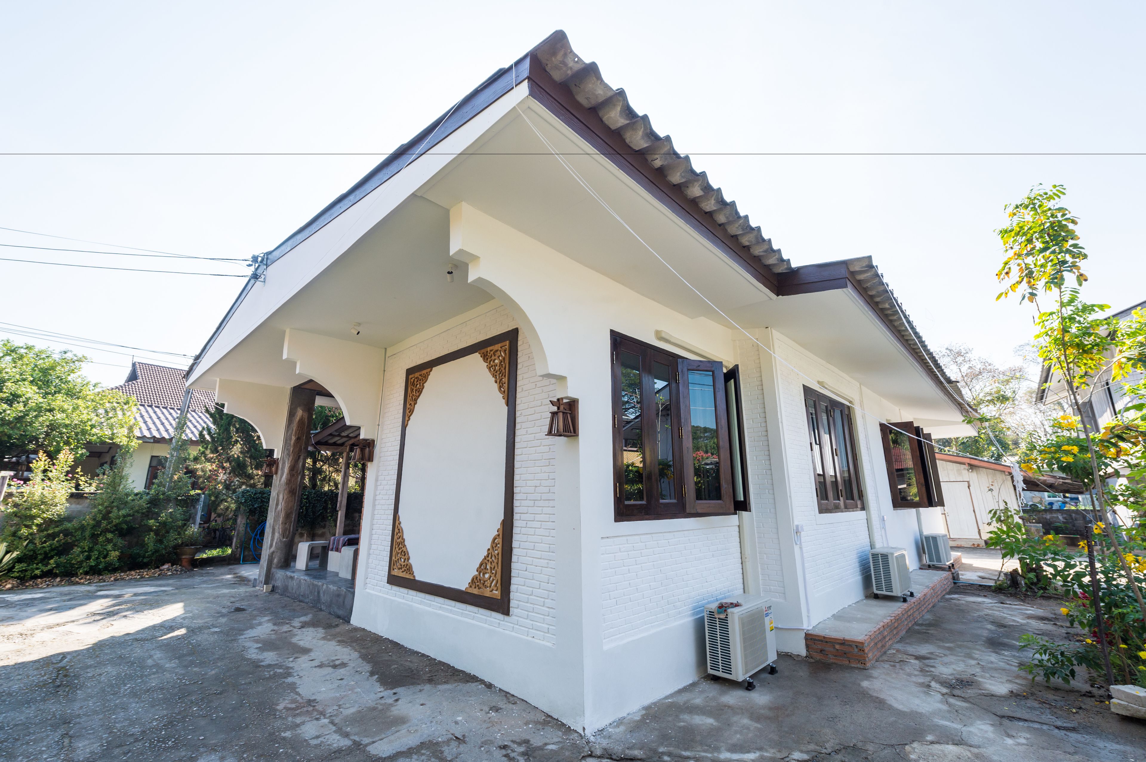 A single-story house with a white exterior, a tiled roof, and a small porch area.