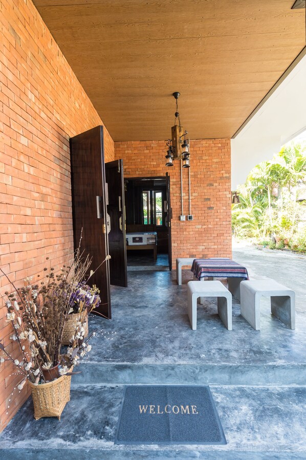 Una entrada moderna con pared de ladrillo, techo de madera y felpudo.
