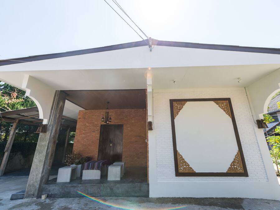 Una casa moderna con fachada blanca, pared de ladrillo y una puerta decorativa grande.