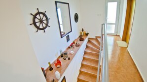 Eine Treppe mit Geländer, ein am Wand befestigtes Schiffswellenrad und ein Spiegel.