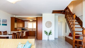 A spacious living area with a wooden staircase, a dining area, and a kitchen. - Birais Beach Studios (Rethymno)