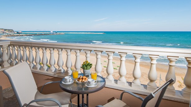 A balcony with a table set for breakfast, overlooking a beach and the sea. - Birais Beach Studios (Rethymno)
