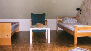 Een knus kamertje met twee houten bedden, een houten stoel en een kleine tafel met een kom.