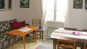 Een woonkamer met een bank, een houten tafel, een stoel, een raam met gordijnen en een schilderij aan de muur.