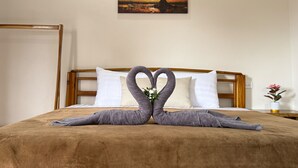 Una habitación de hotel con una cama, un cuadro de un árbol y dos toallas dispuestas en forma de corazón.