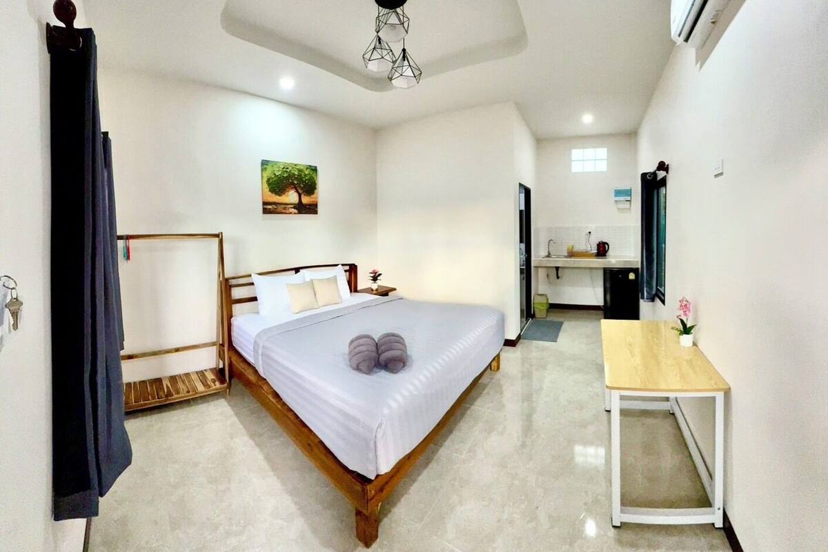 Ein kleines Hotelzimmer mit Bett, Nachttisch und einer kleinen Küchenzeile.