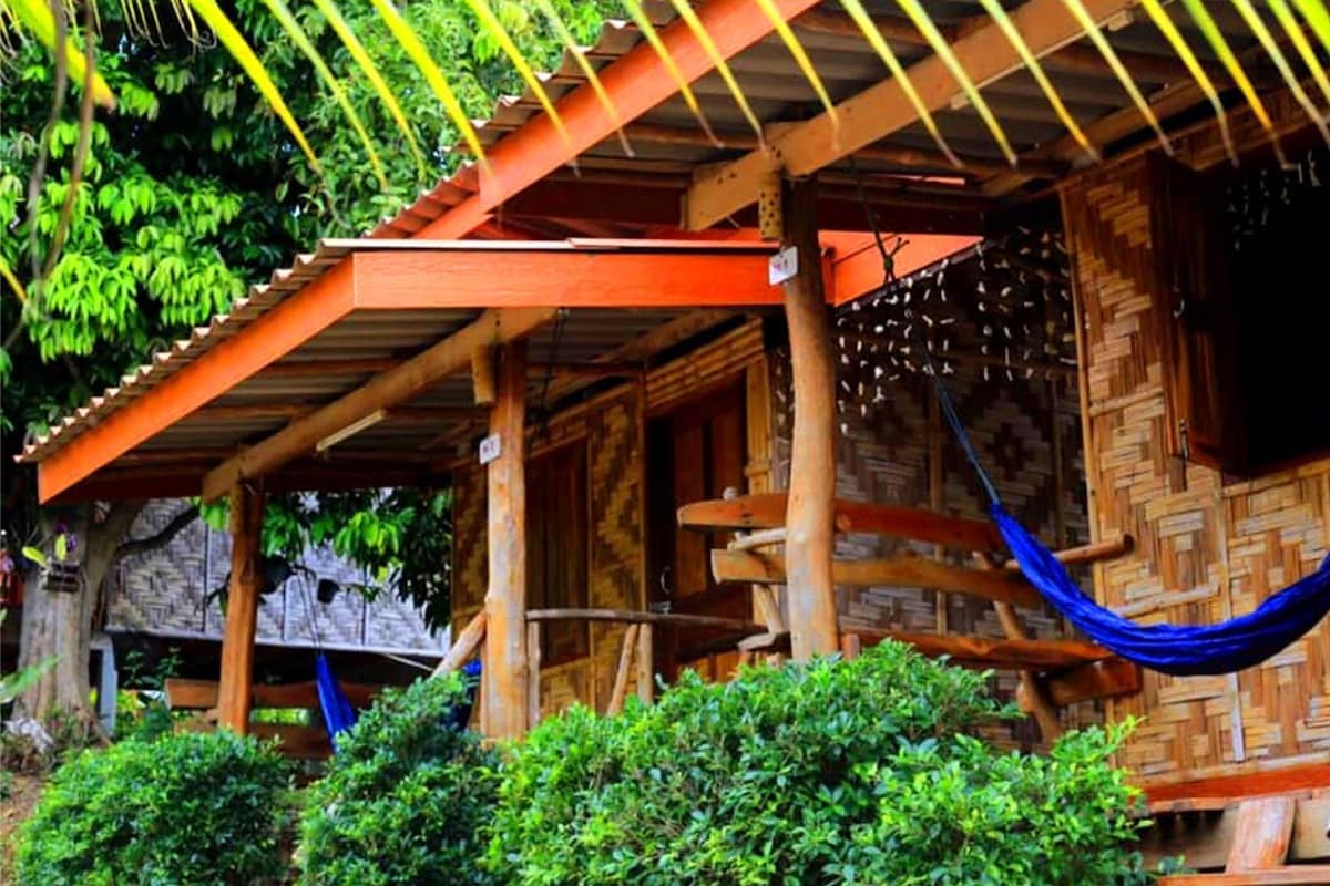 A modern bungalow with a fan, wooden structure, and a hammock.