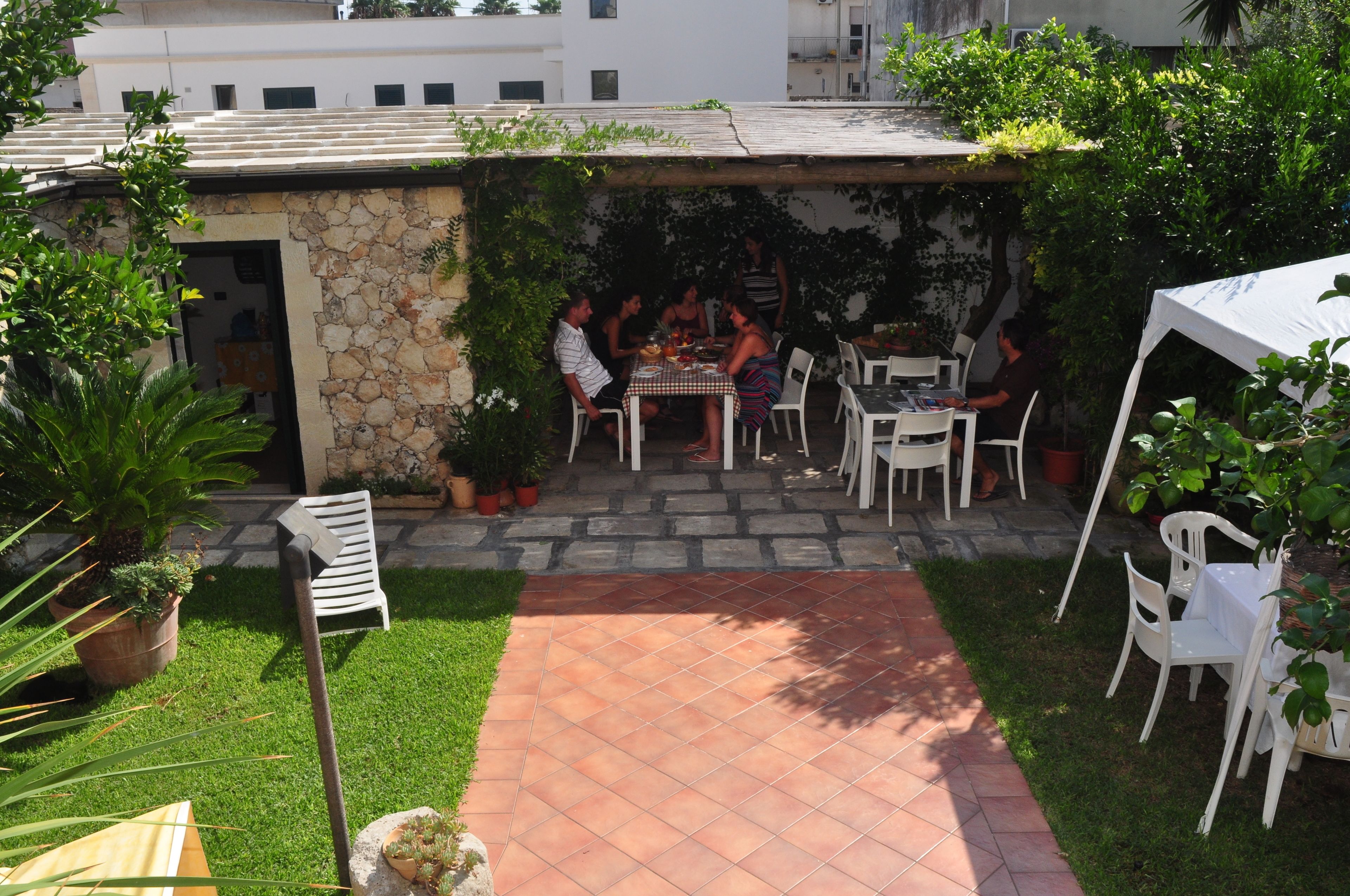 An outdoor patio area with stone walls, white chairs, and a table set for dining.