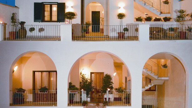 A multi-story building with balconies, arched doorways, and a staircase. - Antico Camino (Muro Leccese)