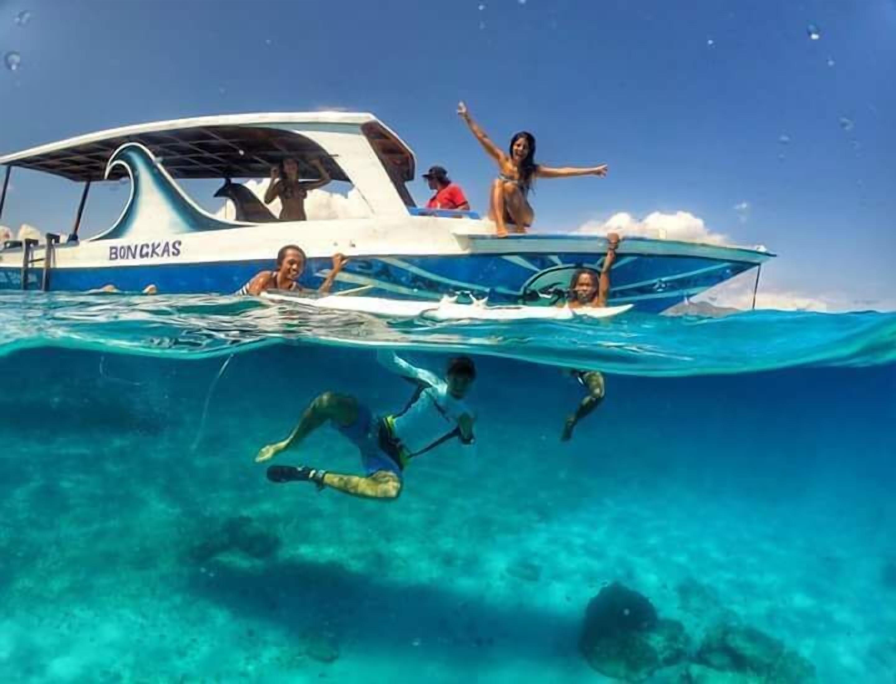 Ein Boot mit der Aufschrift 'BONGKAS', das teilweise im klaren, blauen Wasser versunken ist.