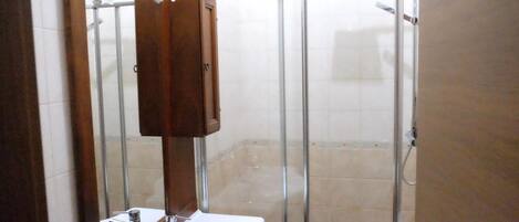 A bathroom with a shower, a sink, and a mirror.