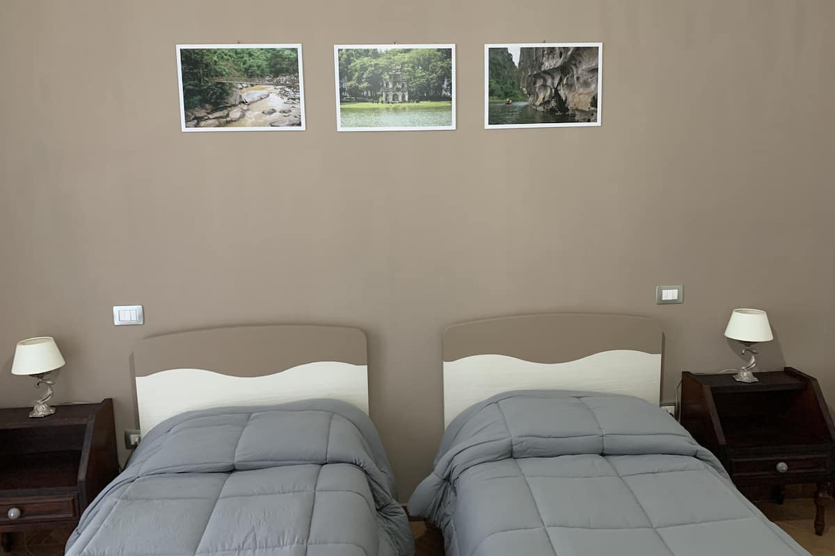 Un dormitorio con dos camas, una mesita de noche a cada lado y tres cuadros en la pared.