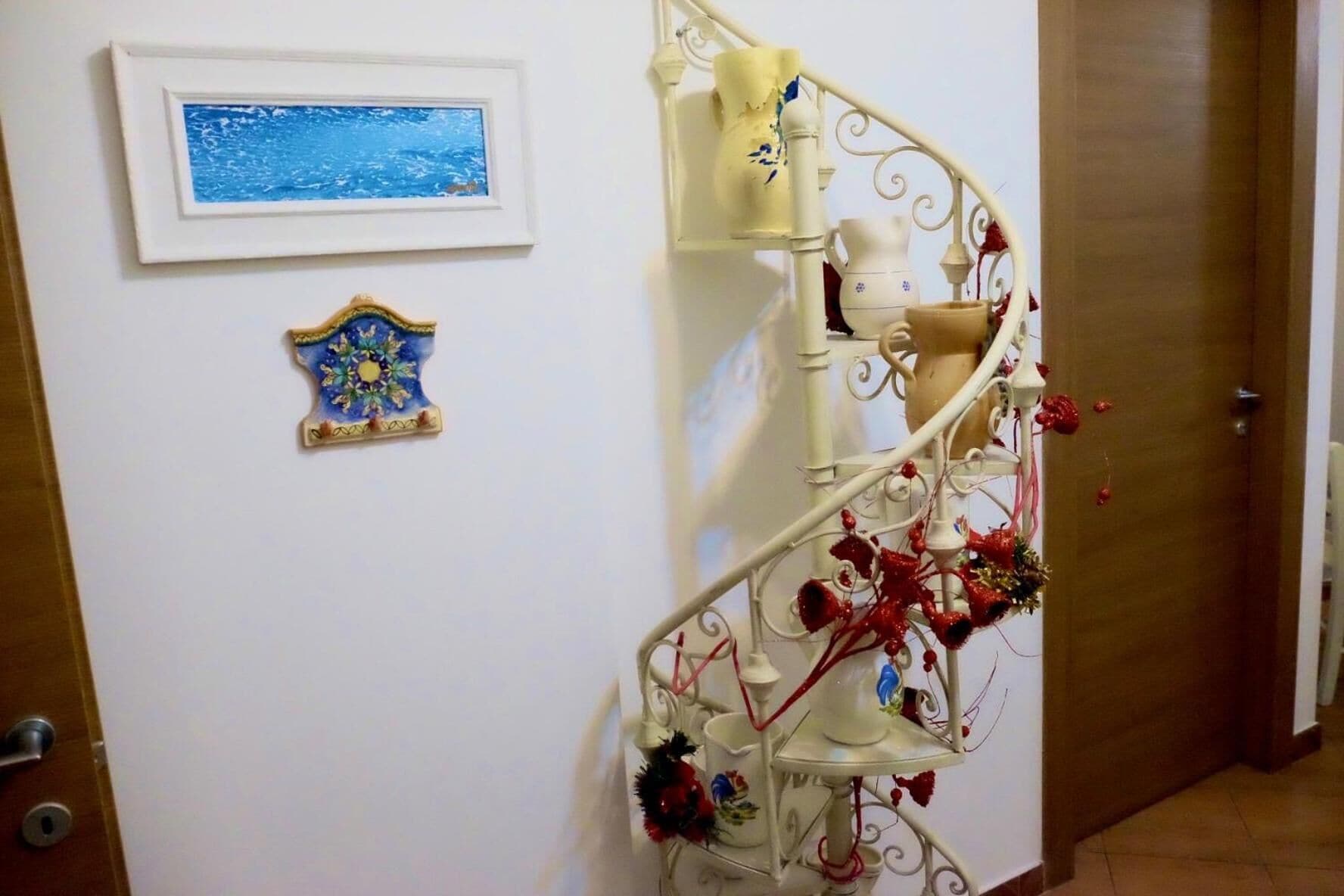 Una escalera con barandilla blanca, un cuadro enmarcado en la pared y un adorno debajo.