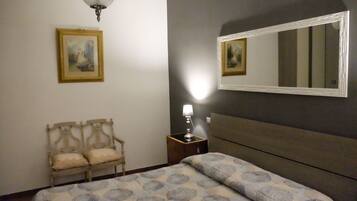 Une chambre à coucher comprenant un lit, une chaise, une table de chevet avec une lampe, et deux tableaux encadrés accrochés au mur.