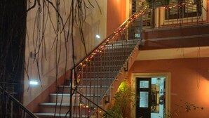 Uma escadaria com corrimão, rodeada por vegetação e luzes de fada.
