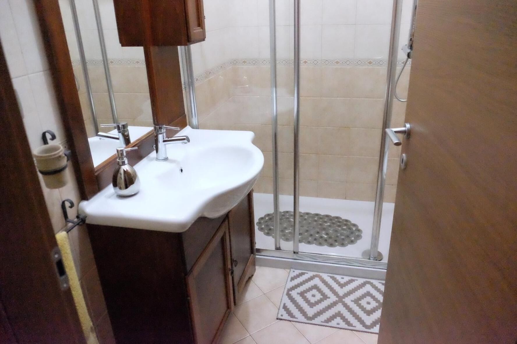 A bathroom with a white sink, a mirror, and a shower area with a glass door.