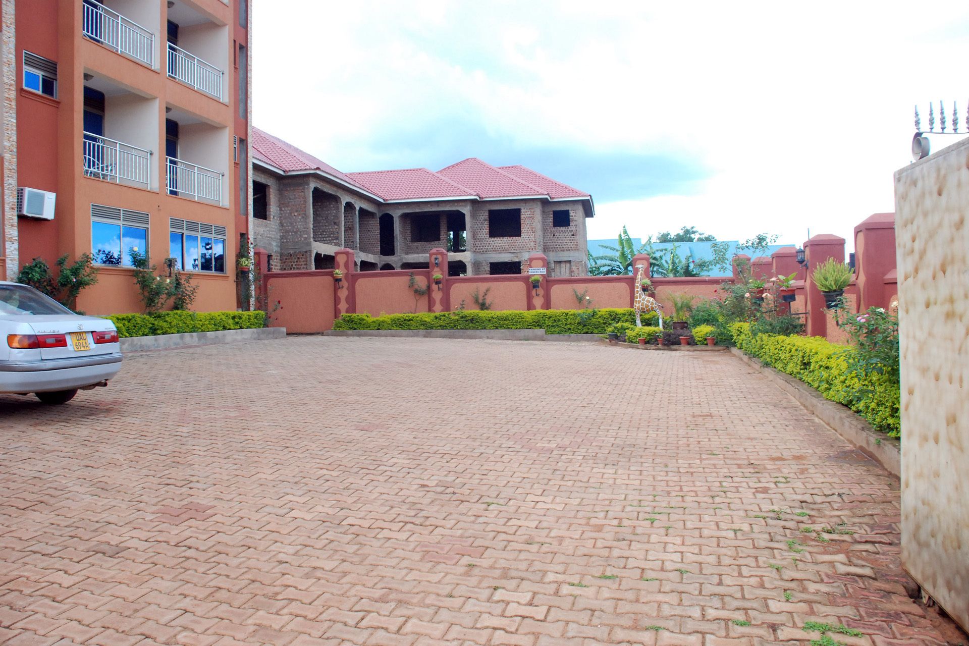 A paved driveway leading to a building with a red roof and multiple balconies.
